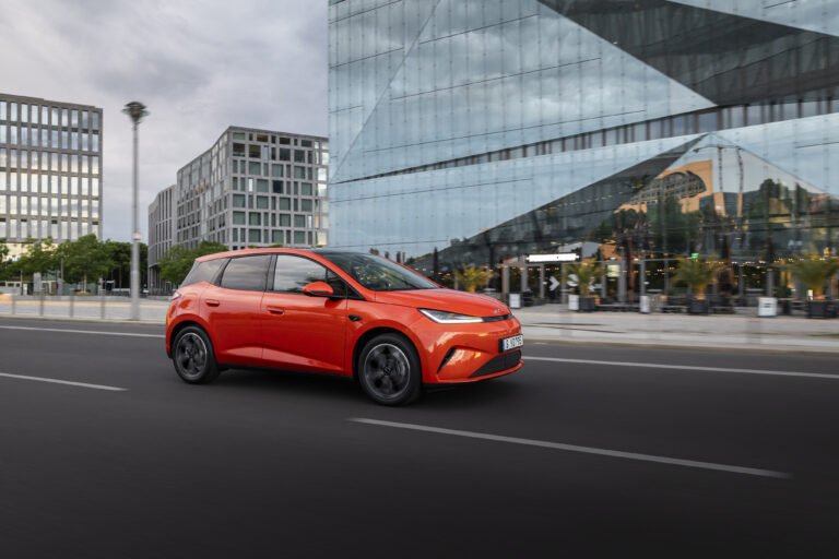 BYD Dolphin G DM-i 2026 vista dinamica 3/4 frontale arancione Orange Sunset