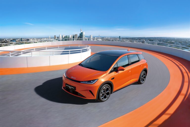 BYD Dolphin G DM-i 2026 vista 3/4 anteriore su rooftop con skyline urbano